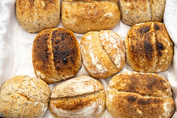 Artisan sourdough homemade craft bread on white textile background. Natural light with soft shadows, close-up top view.