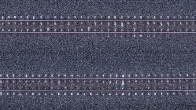 Drone view shows a section of railroad tracks with parallel steel rails set on ballast