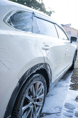 washing a dirty car and wheels with water and a pressure washer