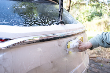 washing a dirty car and wheels with water and a pressure washer