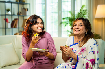 Indian mom and daughter sharing fresh mango slices at home, enjoying seasonal fruit with joy