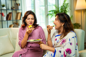 Indian mom and daughter sharing fresh mango slices at home, enjoying seasonal fruit with joy
