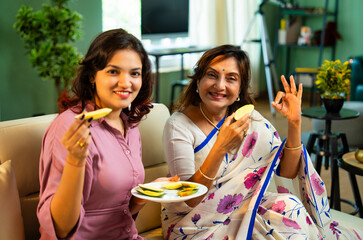 Indian mom and daughter sharing fresh mango slices at home, enjoying seasonal fruit with joy