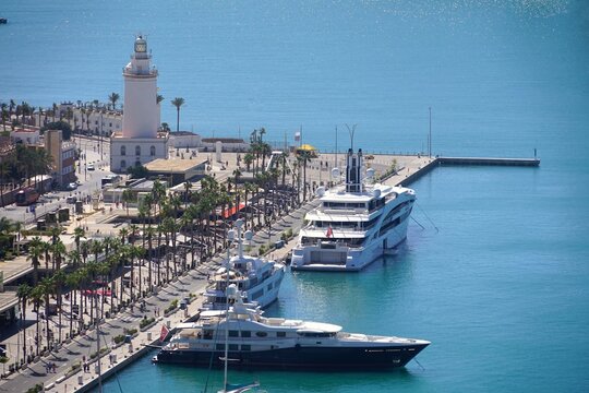 view from Mirador de Gibralfaro to the harbor with the promenade with luxury yachts and the lighthouse La Farola de M&aacute;laga, Costa del Sol