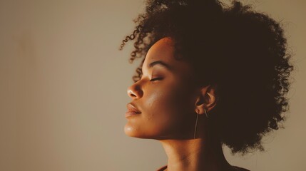 Thoughtful young woman with curly hair and closed eyes, basking in the warm sunlight.