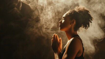 Thoughtful young woman praying with closed eyes in a dark room with smoky atmosphere.