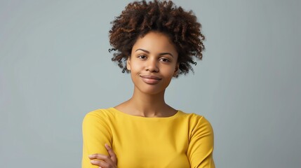 Beautiful young African American woman with curly hair wearing a yellow dress smiling at the camera.