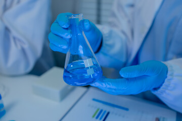 when in a lab, scientists wear lab coats, rubber gloves, and safety goggles, two chemists are...