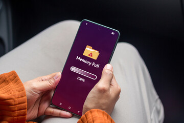 Woman holding a smartphone with memory space full notification on phone screen