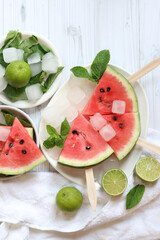 Ripe watermelon pieces on sticks like ice cream. Watermelon, lime and mint. Summer fruits...