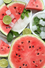 Ripe watermelon pieces on sticks like ice cream. Watermelon, lime and mint. Summer fruits background. Flat lay. Watermelon slices in white plate top view, wooden table and lime halves. Summer food