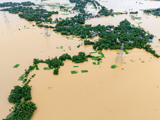 Fototapeta na wymiar Drone shot of rural flood-affected area, houses submerged under brown floodwater.
