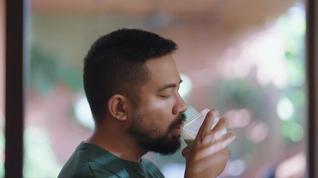 Relaxed scenes of man sipping homemade matcha latte at home. Natural lifestyle moments showing calmness, daily ritual, and enjoyment of a traditional green tea drink.