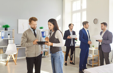 Team of company employees working together in office, talking in small groups. Colleagues...