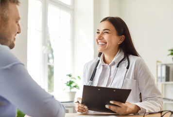 Positive woman doctor or nurse provides medical aid and care to a patient in a hospital office....