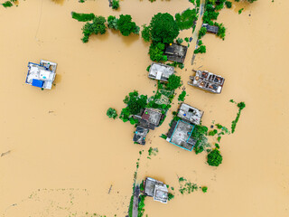 Flooded village aerial with muddy water covering houses and farmland.