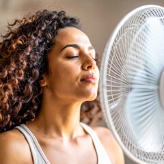 A person in front of a fan with an expression of feeling hot, trying to cool down a bit during the summer. Temperature, cool down, air, scorching