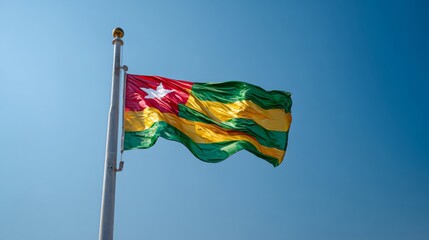 Realistic depiction of the flag of Togo waving in a clear blue sky during daytime hours