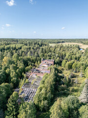 Aerial view of a long-abandoned brick structure hidden in the dense forest landscape. The roofless ruins are overtaken by nature.