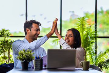 Indians Celebrating business success together with fist bump, high five in modern office workspace