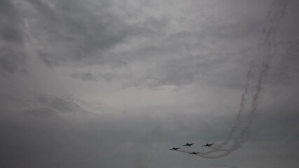 Aerobatic team dives in tight formation leaving sharp smoke trails slicing through moody sky as symmetry speed and teamwork fuse in a bold display of precision and control