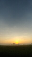 Vertical wide-angle shot of a calm morning sky with deep blue fading into warm sunrise hues,...