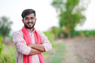 young indian farmer standing at green agricultural field
