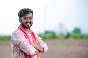 young indian farmer standing at green agricultural field