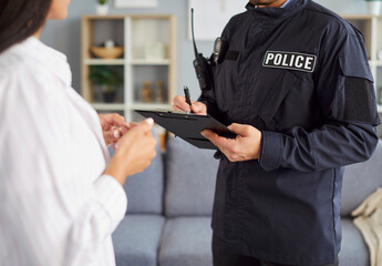 Portrait of police man officer wearing uniform talking to witnesses or interrogating a young woman...