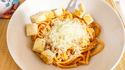 Bucatini seasoned with tomato sauce, tofu and grated cheese creating a vegan meal