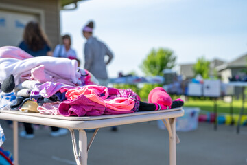 Pile of secondhand girls cloths on a folding table of a yard sale