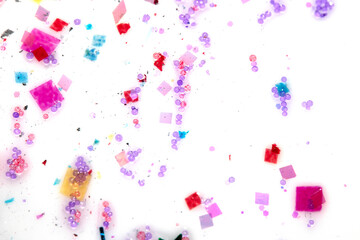 Close up of confetti tinsel glitter and shining stars on white background
