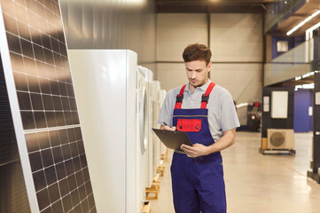 Man is inspecting or taking inventory of solar panels in a shop. Ensures the photovoltaic panels...
