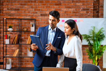 Chasing project deadline indoors, Indian corporate team discusses work using tablet in office