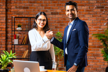 Indian professionals finalize deal with handshake, smiling after discussion in modern office