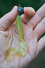 A man holds a silicone fishing lure in his hand. Fishing gear, sport fishing.