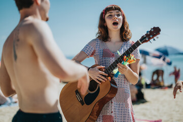 A cheerful woman singing and playing guitar surrounded by friends on a lively summer beach.