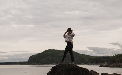 woman wearing a sporty outfit is walking on top of a rock in front of a lake and hills in the...