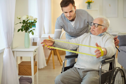 Wheelchair senior man elastic band exercises for arms with kind medical brother, consultant nursing, health and social care of elderly, doctor, male geriatric nurse helping old patient rehabilitation