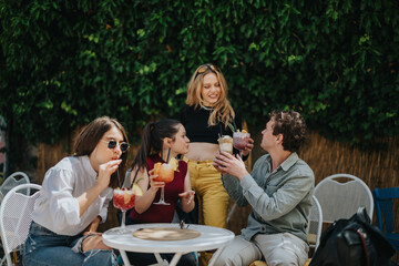 Group of friends having a joyful gathering, enjoying beverages in a lush, vibrant setting. The...