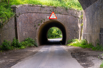 Narrow road passing under low bridge in United Kingdom