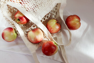 Nectarine. Ripe juicy organic nectarines (peaches) in a reusable mesh cotton shopping bag. plastic...