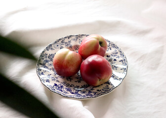 Nectarines(peaches) in a vintage blue patterned plate on a clean, soft cloth