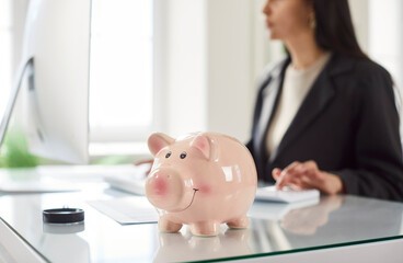 Piggy bank on office table, woman investing money, planning future, manage finances to save money,...