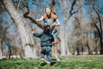 A young child interacting with an adult in a sunny park setting during springtime, symbolizing...