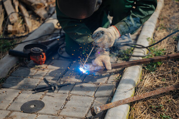 A man works with a welding machine. Sparks from welding. Joining metal parts using a welding machine.
