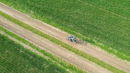 Aerial view of a cyclist on a bicycle riding on a country road between green fields. Cycling traveler riding across the field on a dirt road.