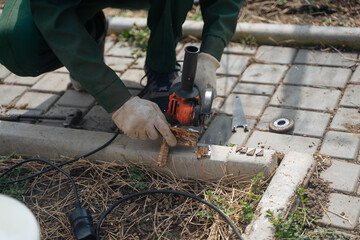 A man cuts off a piece of metal with a grinder. The grinder is in the hands of a master. Construction works.
