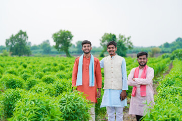 young indian farmer group standing together at green agricultural field