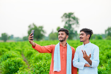 two young indian farmer taking selfie in green agricultural field